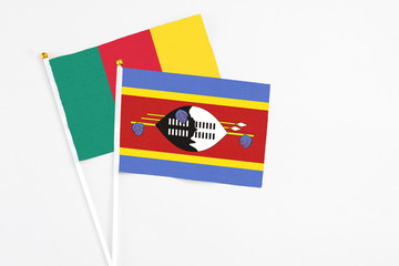 Swaziland and Cameroon stick flags on white background. High quality fabric, miniature national flag. Peaceful global concept.White floor for copy space.