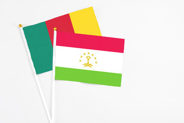 Tajikistan and Cameroon stick flags on white background. High quality fabric, miniature national flag. Peaceful global concept.White floor for copy space.
