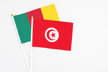 Tunisia and Cameroon stick flags on white background. High quality fabric, miniature national flag. Peaceful global concept.White floor for copy space.