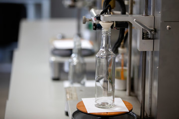 Glassworks. Hands hold a glass bottle over the device. Quality control of glass containers