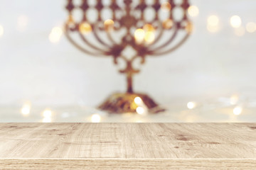 religion image of empty wooden table in front of jewish holiday Hanukkah background with menorah (traditional candelabra). For product display