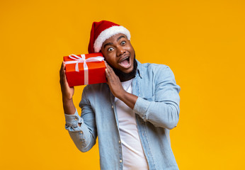 Crazy black guy in Santa hat holding Christmas gift box