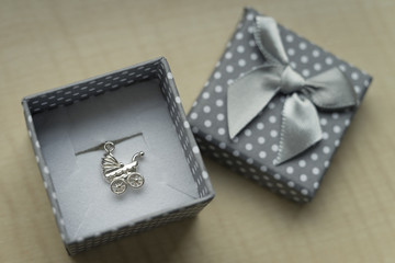 Silver pendant in a box in the shape of a stroller.