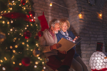 Senior couple looking through old photo album on Christmas Eve