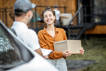 Portrait of a happy client with a male courier delivering goods by vehicle to a woman home, workman...