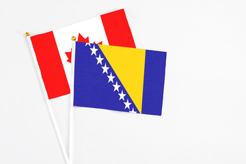 Bosnia Herzegovina and Canada stick flags on white background. High quality fabric, miniature national flag. Peaceful global concept.White floor for copy space.