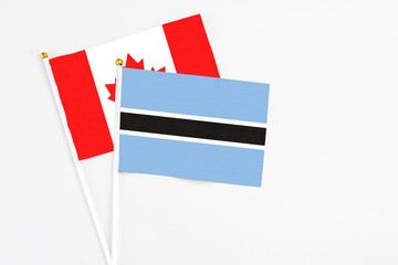 Botswana and Canada stick flags on white background. High quality fabric, miniature national flag. Peaceful global concept.White floor for copy space.