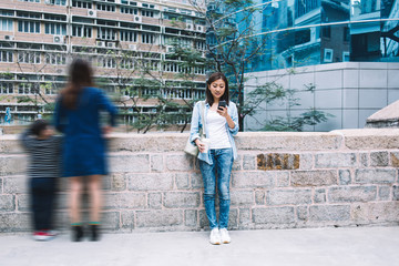 Asian woman standing with phone on urban background