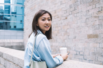 Fototapeta na wymiar Friendly Asian modern casual woman relaxing on street