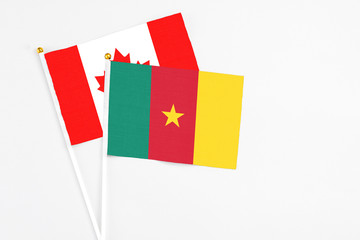 Cameroon and Canada stick flags on white background. High quality fabric, miniature national flag. Peaceful global concept.White floor for copy space.