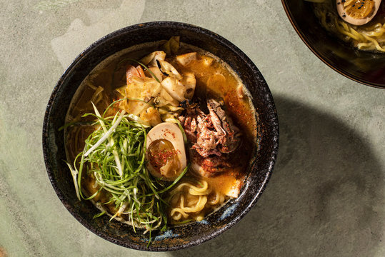 Bowl of ramen with meat and egg on green table