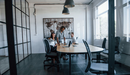 View through the glass. Young business people in formal clothes working in the office