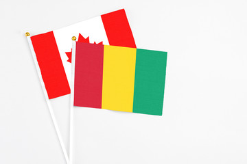 Guinea and Canada stick flags on white background. High quality fabric, miniature national flag. Peaceful global concept.White floor for copy space.