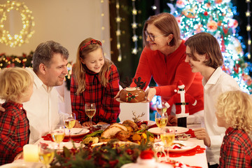 Family with kids having Christmas dinner at tree