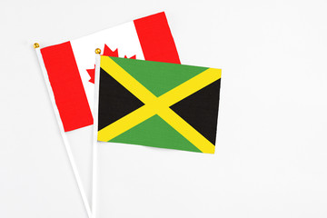 Jamaica and Canada stick flags on white background. High quality fabric, miniature national flag. Peaceful global concept.White floor for copy space.