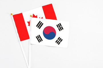 South Korea and Canada stick flags on white background. High quality fabric, miniature national flag. Peaceful global concept.White floor for copy space.