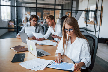 Blonde girl reads document. Young business people in formal clothes working in the office