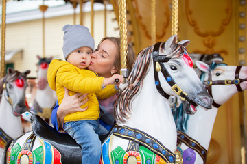 Fototapeta na wymiar Mom with a cheerful baby on a carousel.