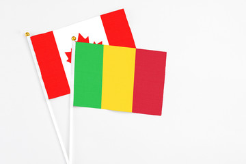 Mali and Canada stick flags on white background. High quality fabric, miniature national flag. Peaceful global concept.White floor for copy space.