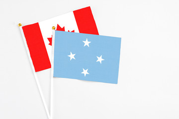 Micronesia and Canada stick flags on white background. High quality fabric, miniature national flag. Peaceful global concept.White floor for copy space.