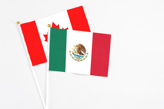 Mexico and Canada stick flags on white background. High quality fabric, miniature national flag. Peaceful global concept.White floor for copy space.