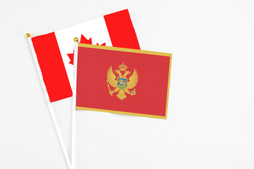 Montenegro and Canada stick flags on white background. High quality fabric, miniature national flag. Peaceful global concept.White floor for copy space.