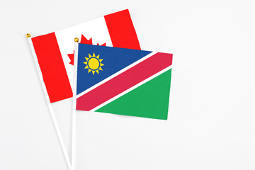 Namibia and Canada stick flags on white background. High quality fabric, miniature national flag. Peaceful global concept.White floor for copy space.