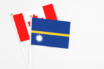 Nauru and Canada stick flags on white background. High quality fabric, miniature national flag. Peaceful global concept.White floor for copy space.