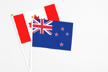 Fototapeta premium New Zealand and Canada stick flags on white background. High quality fabric, miniature national flag. Peaceful global concept.White floor for copy space.