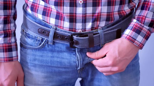 Man is scratching his dick in jeans, hands closeup. Concept of sexually transmitted diseases.