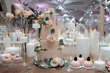 Dessert table for a party. Cake, cupcakes, sweetness and flowers. Table with desserts and candles. Romantic design. Dessert table at wedding reception