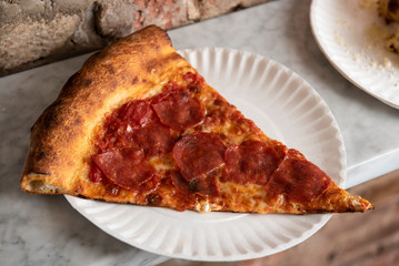 Slice of pepperoni pizza on a paper plate