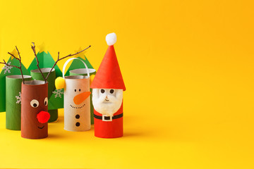 Paper toy santa, snowman, reindeer, grinch, xmas tree for Happy new year Merry Christmas party. Easy crafts for kids on yellow background, idea from toilet rool tube, recycle