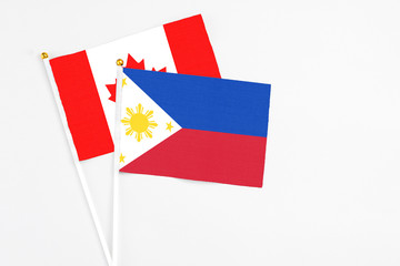 Philippines and Canada stick flags on white background. High quality fabric, miniature national flag. Peaceful global concept.White floor for copy space.