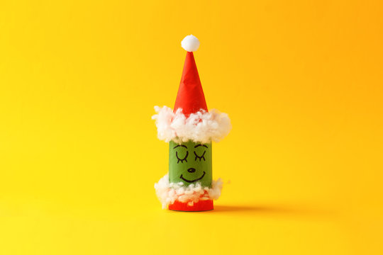 Paper toy grinch for Happy new year Merry Christmas party. Easy crafts for kids on yellow background, simple diy idea from toilet rool tube, recycle concept, copy space