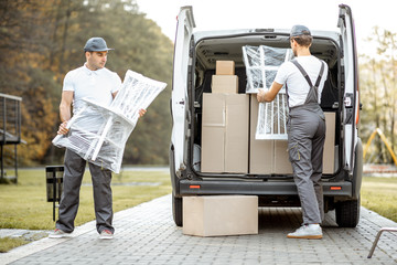 Delivery company employees unloading cargo van vehicle, delivering some goods and furniture to a...