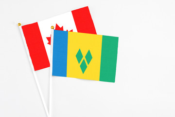 Saint Vincent And The Grenadines and Canada stick flags on white background. High quality fabric,...