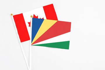 Seychelles and Canada stick flags on white background. High quality fabric, miniature national flag. Peaceful global concept.White floor for copy space.