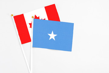 Somalia and Canada stick flags on white background. High quality fabric, miniature national flag. Peaceful global concept.White floor for copy space.
