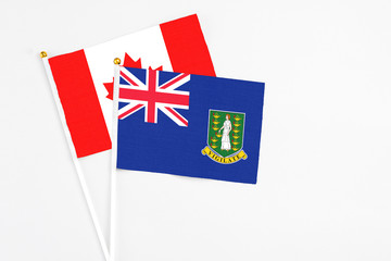 Fototapeta premium British Virgin Islands and Canada stick flags on white background. High quality fabric, miniature national flag. Peaceful global concept.White floor for copy space.