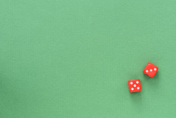 Dice of red color on a green background. Top view, copy space. Gambling concept background