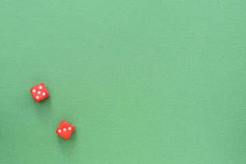 Dice of red color on a green background. Top view, copy space. Gambling concept background