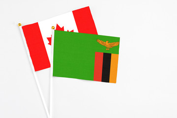 Zambia and Canada stick flags on white background. High quality fabric, miniature national flag. Peaceful global concept.White floor for copy space.