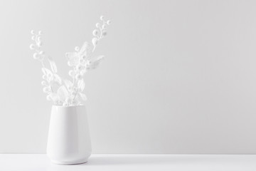 Winter composition of white branches, berries and leaves with sparkles in vase on white background....