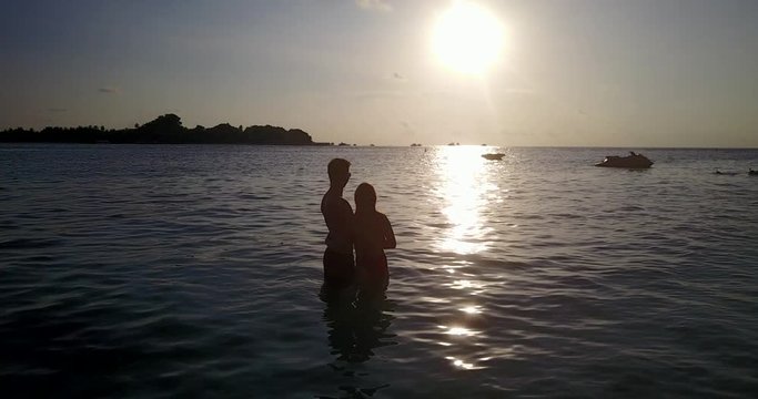 Silhouette of engagement couple enjoying beautiful romantic sunset from shallow water of lagoon in Barbados
