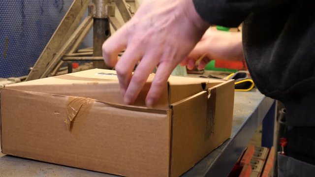 Man unboxes a new disc brake rotor and pads so he can install them on his car