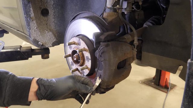 Mechanic removes the caliper pin on the disc brake component of a car to replace or repair the braking system