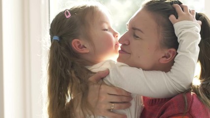 Daughter kissing her happy mother and embraces her, they are at home. Happy mother's day