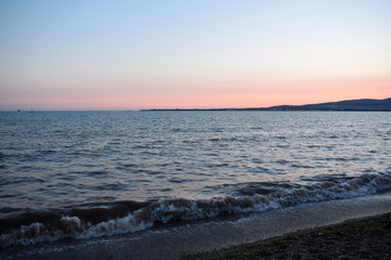 Fototapeta premium Sunset over the sea. The Sun sets behind the mountains