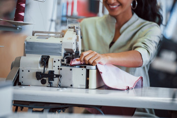 Dressmaker woman sews clothes on sewing machine in factory